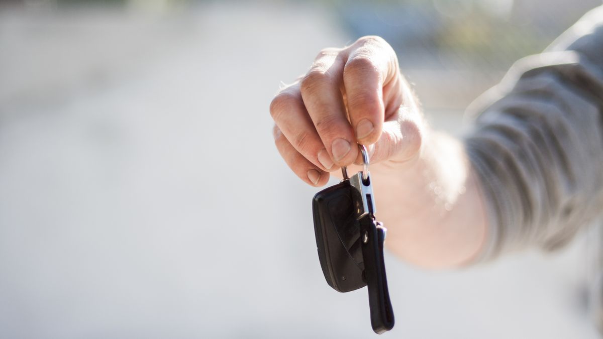 A hand holding out a set of car keys, ready to trade in a used car at a Manchester, NH dealership