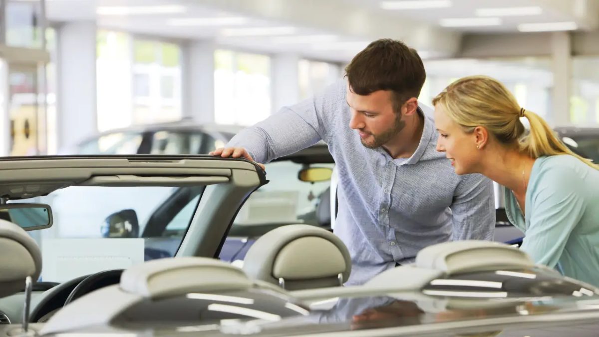 A couple looks over a car at a dealership while weighing their options for a vehicle loan with negative equity